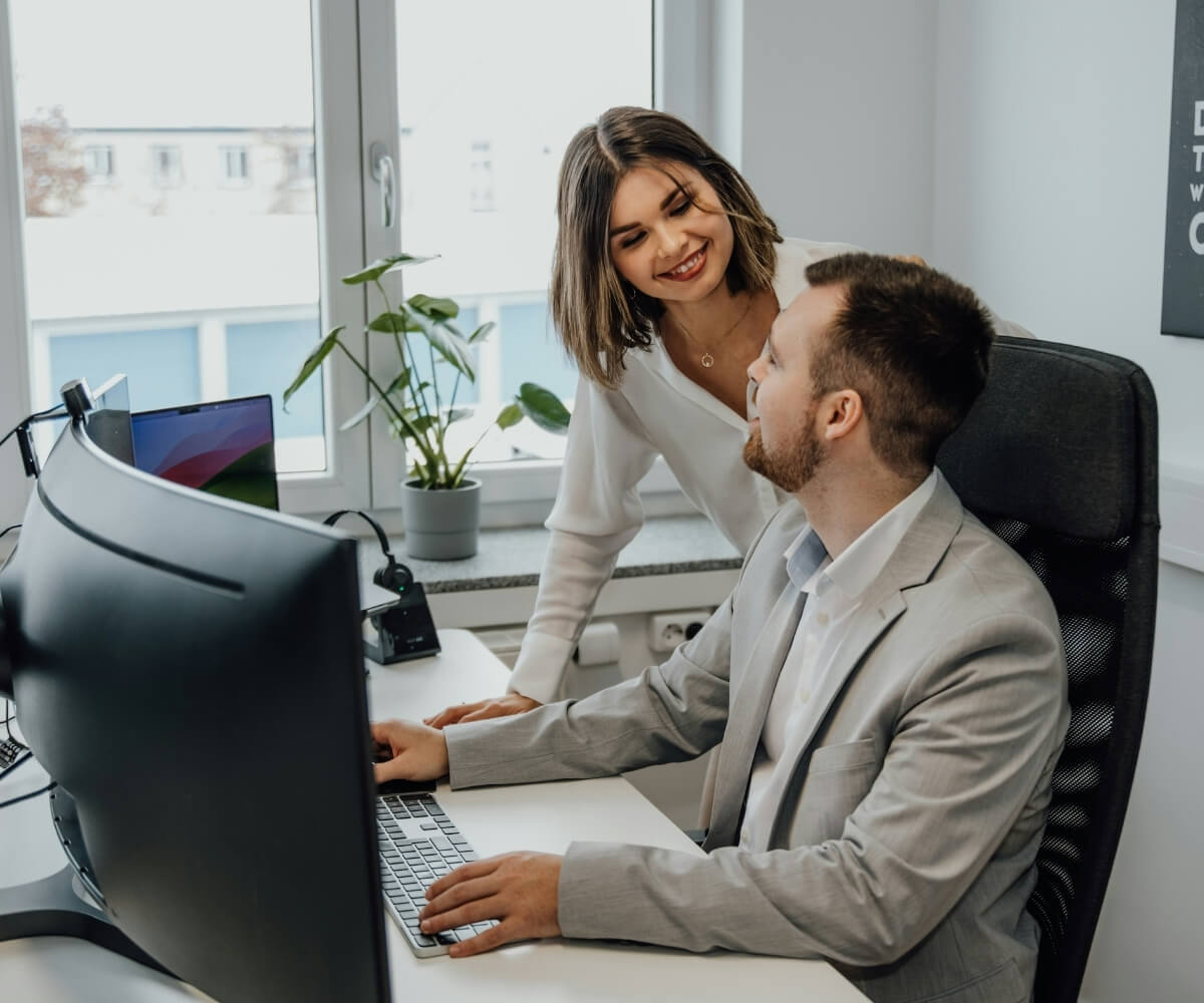 Deux collaborateurs souriants travaillant ensemble au bureau